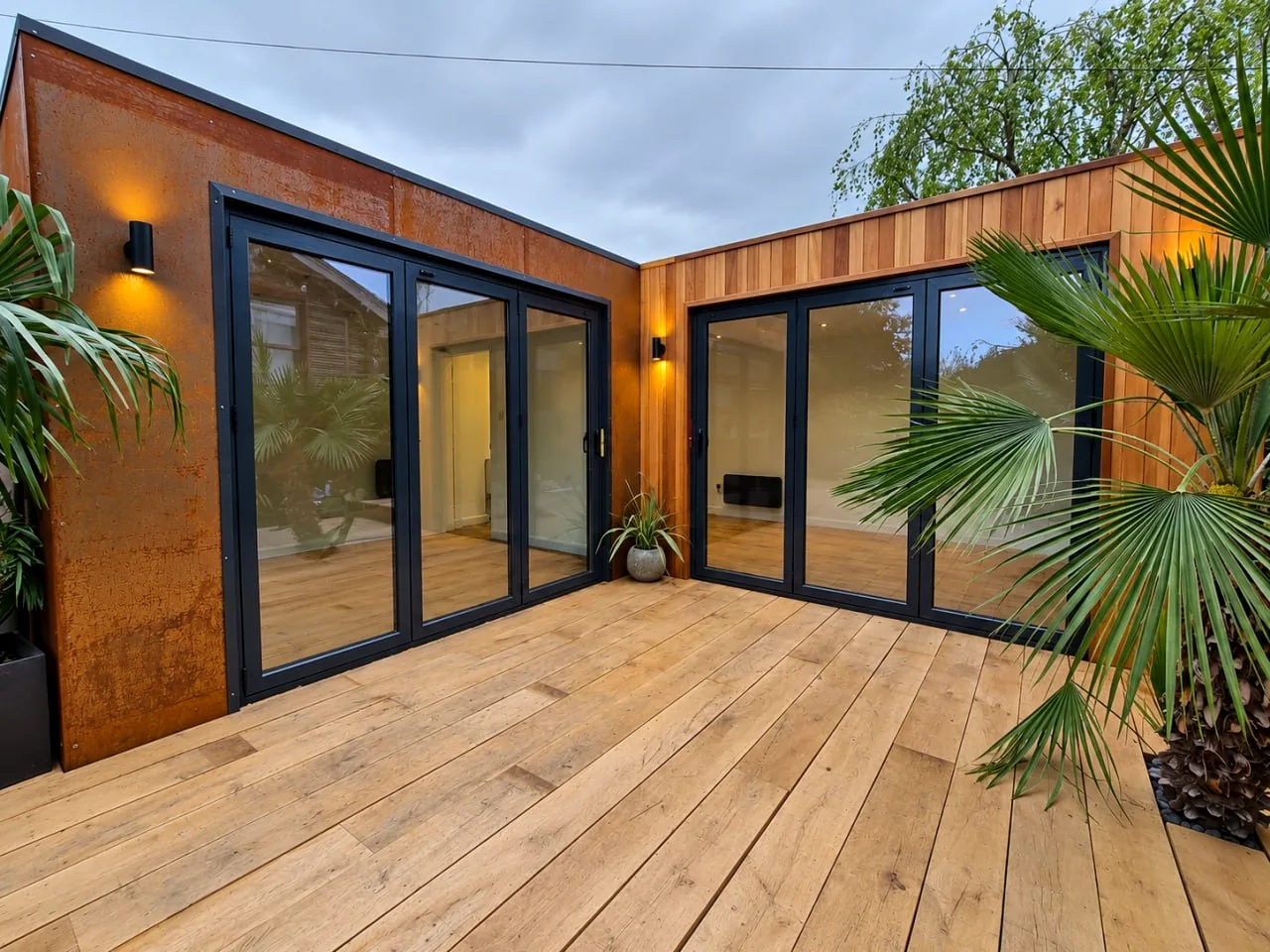 Connected timber garden buildings with deck and planted setting
